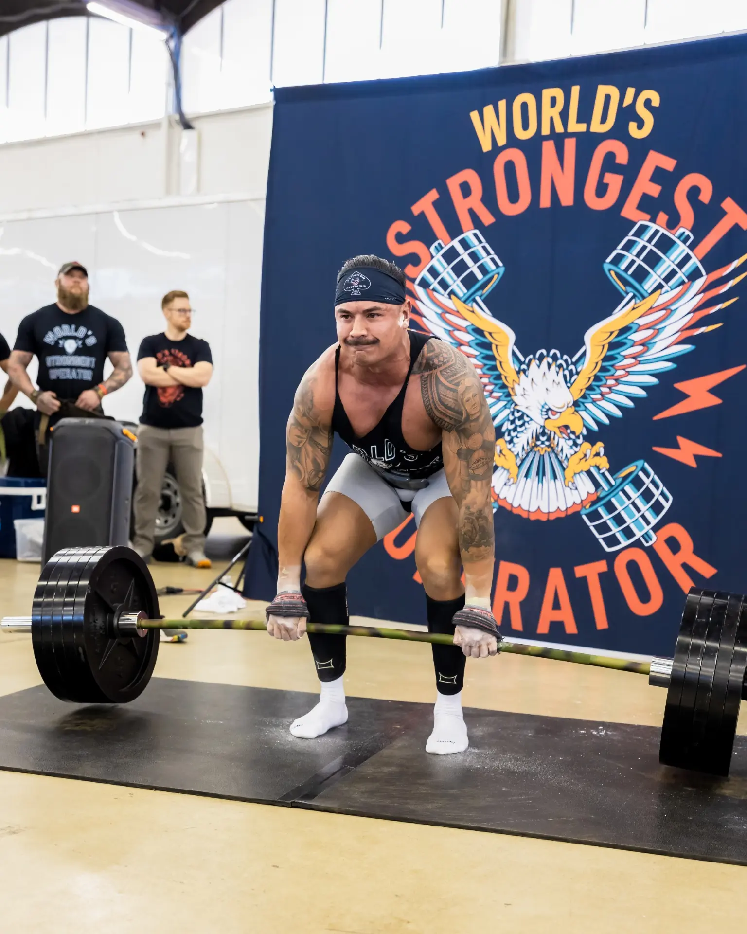Athlete setting up for a heavy barbell deadlift at a strongman competition